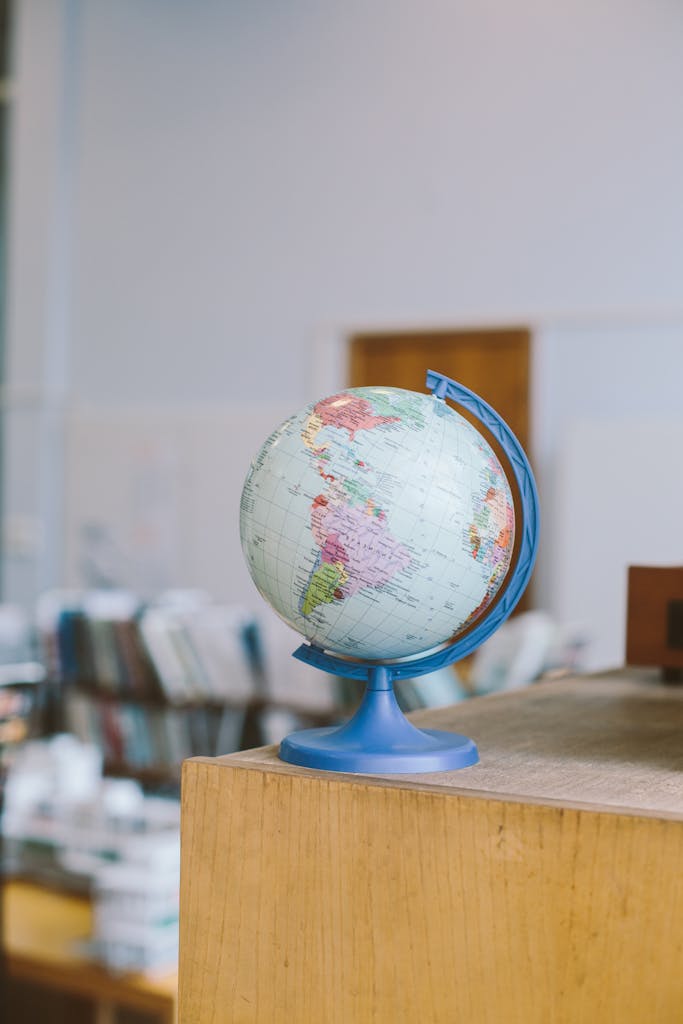 Educational Globe on Wooden Shelf in Library A globe placed on a wooden shelf in a quiet library setting, symbolizing global education and learning.