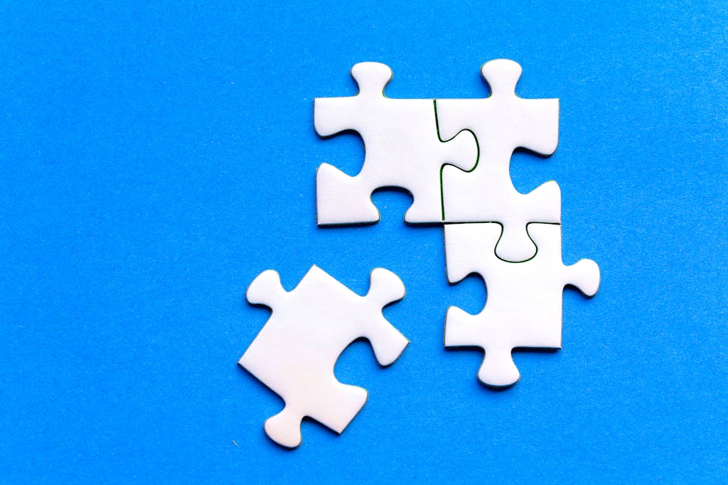 Photo by Mike van Schoonderwalt White jigsaw puzzle pieces against a solid blue background, showcasing a flat lay arrangement.